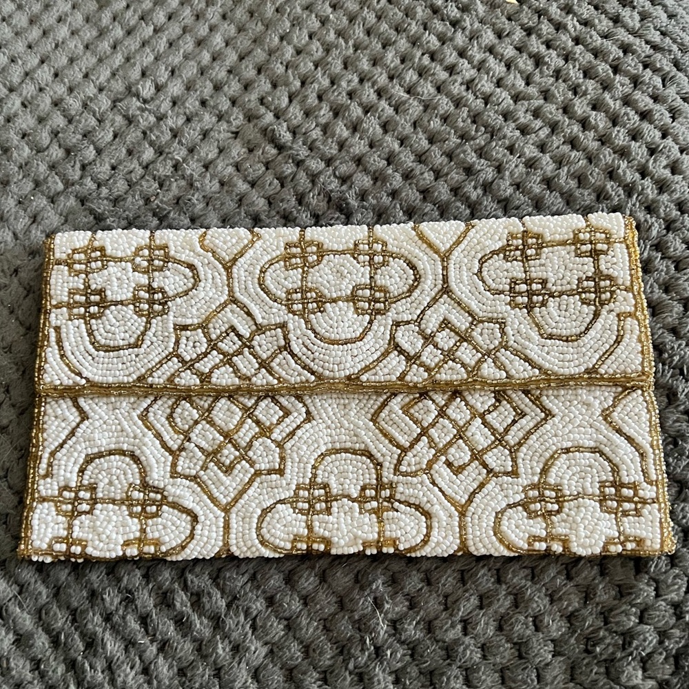 Beaded white and gold clutch made in India. Interior pocket, snap closure flap.
